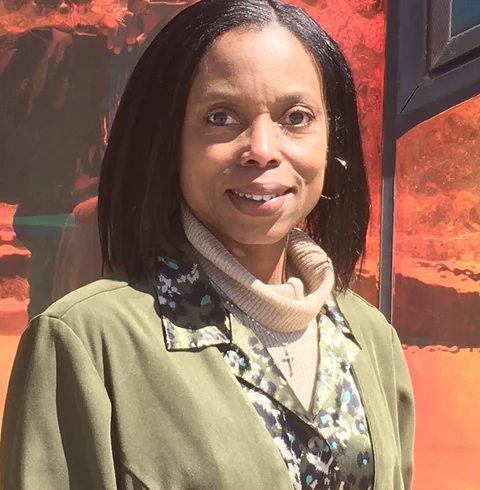 Dorice McGhee smiling in front of orange glass.